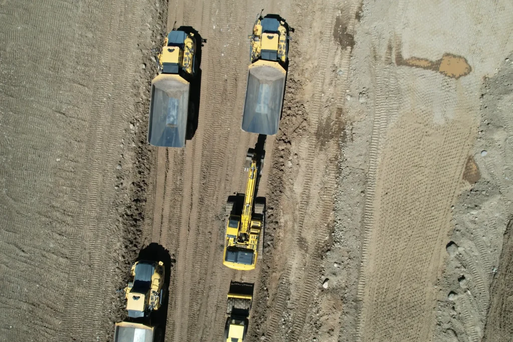 Aerial drone photo of haul trucks and an excavator working on a graded road